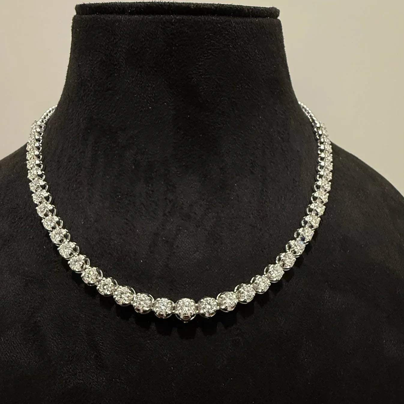 Elegant round cut lab grown diamond necklace set displayed on a black mannequin stand.