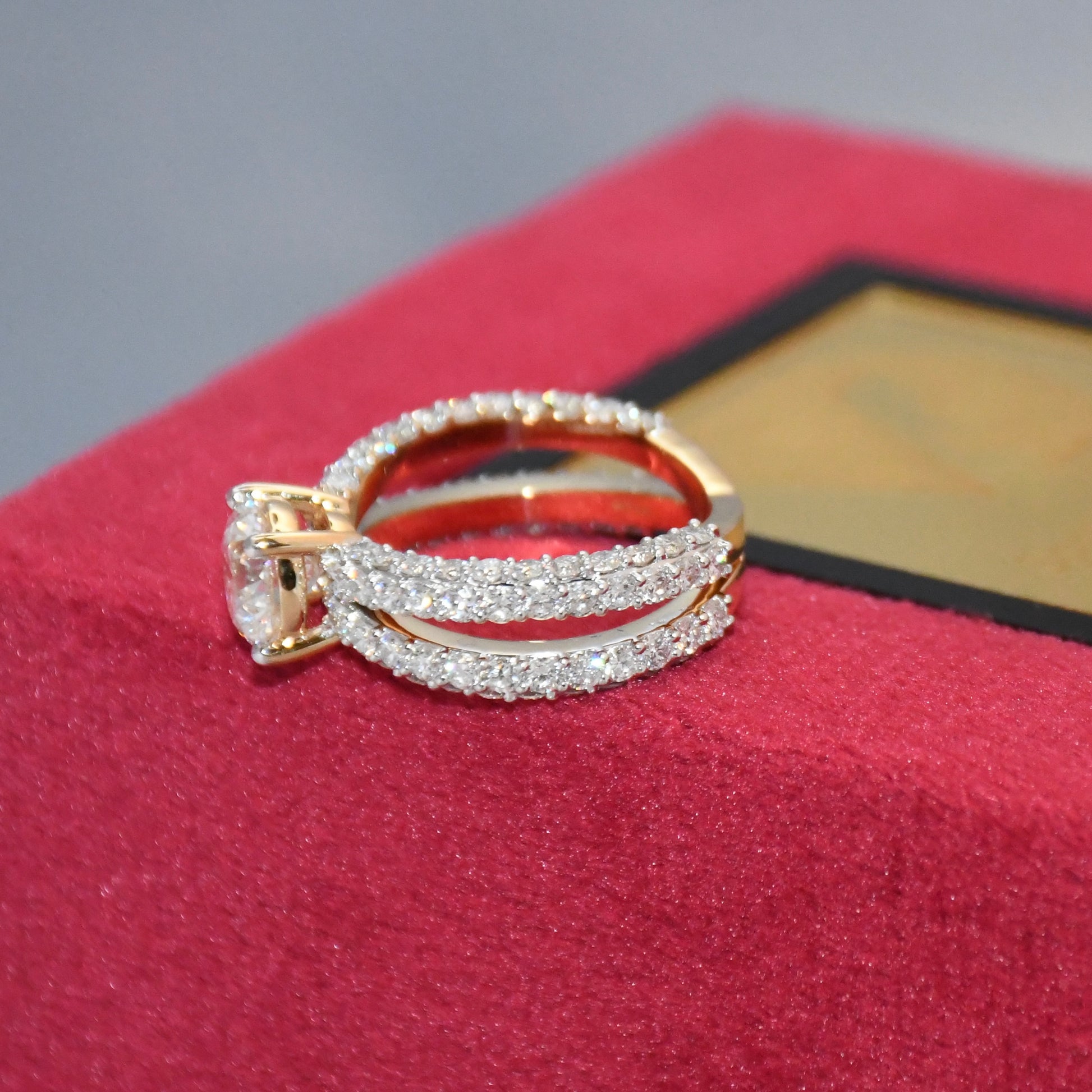 Gold and lab grown diamond ring on a red jewelry box with a blurred background
