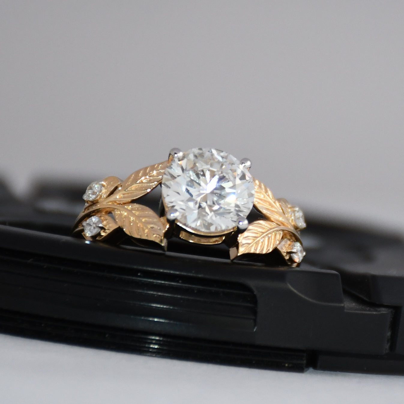 Gold ring with lab grown diamond on a black surface