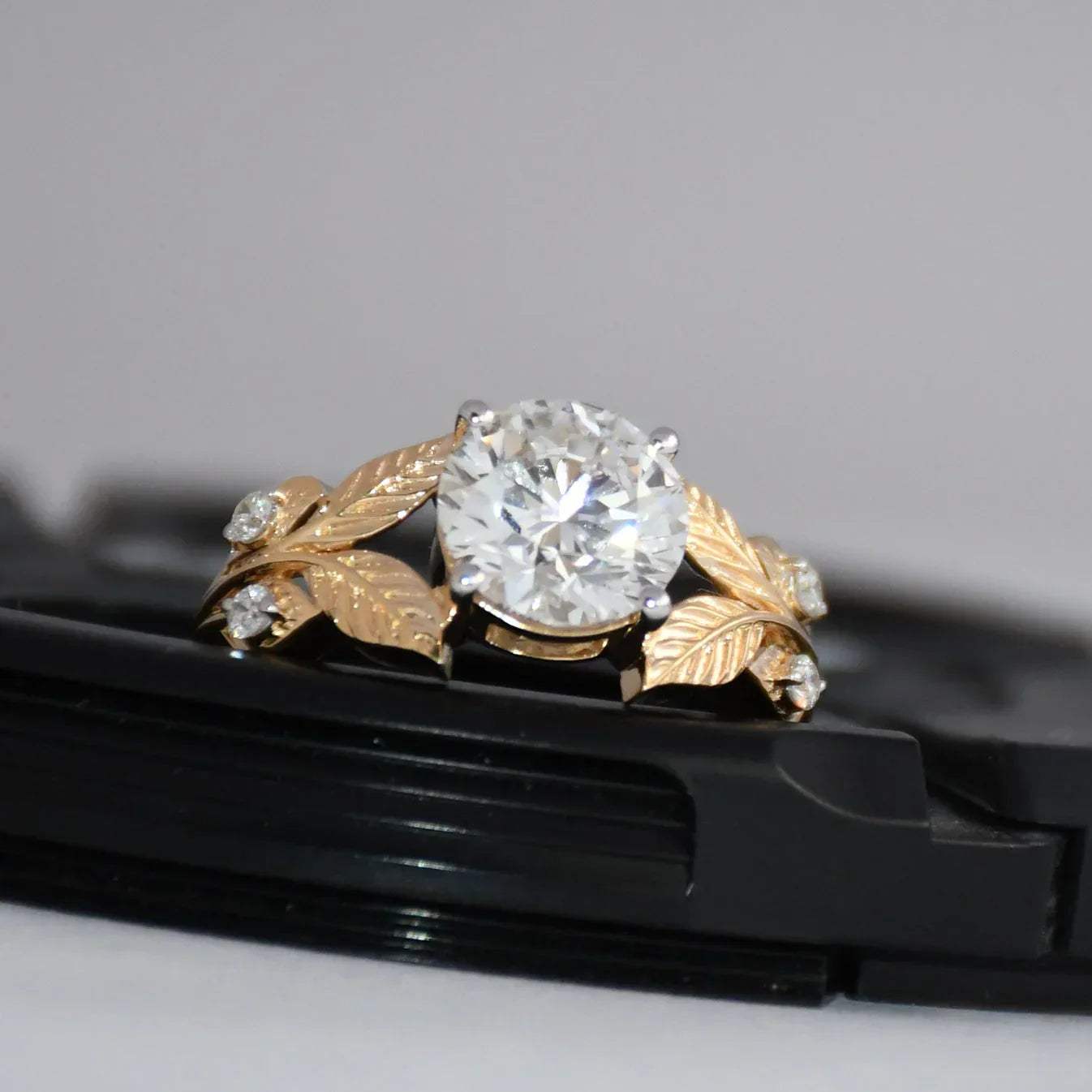 Gold ring with lab grown diamond on a black surface
