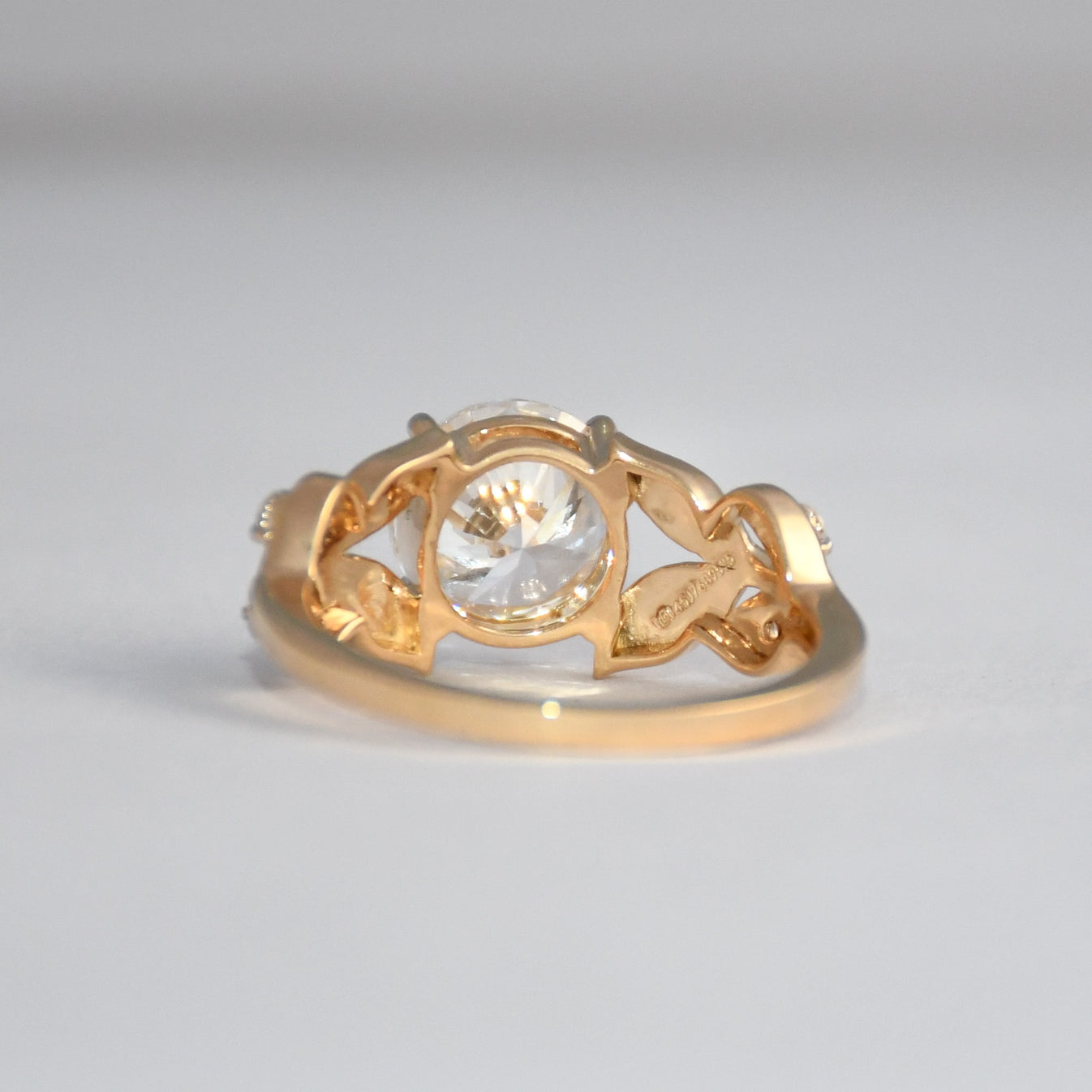 Gold ring with a lab grown diamond on a light gray background.