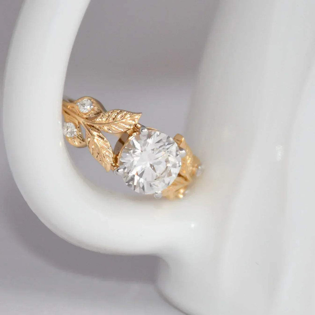 Gold ring with a lab grown diamond on a gray background.