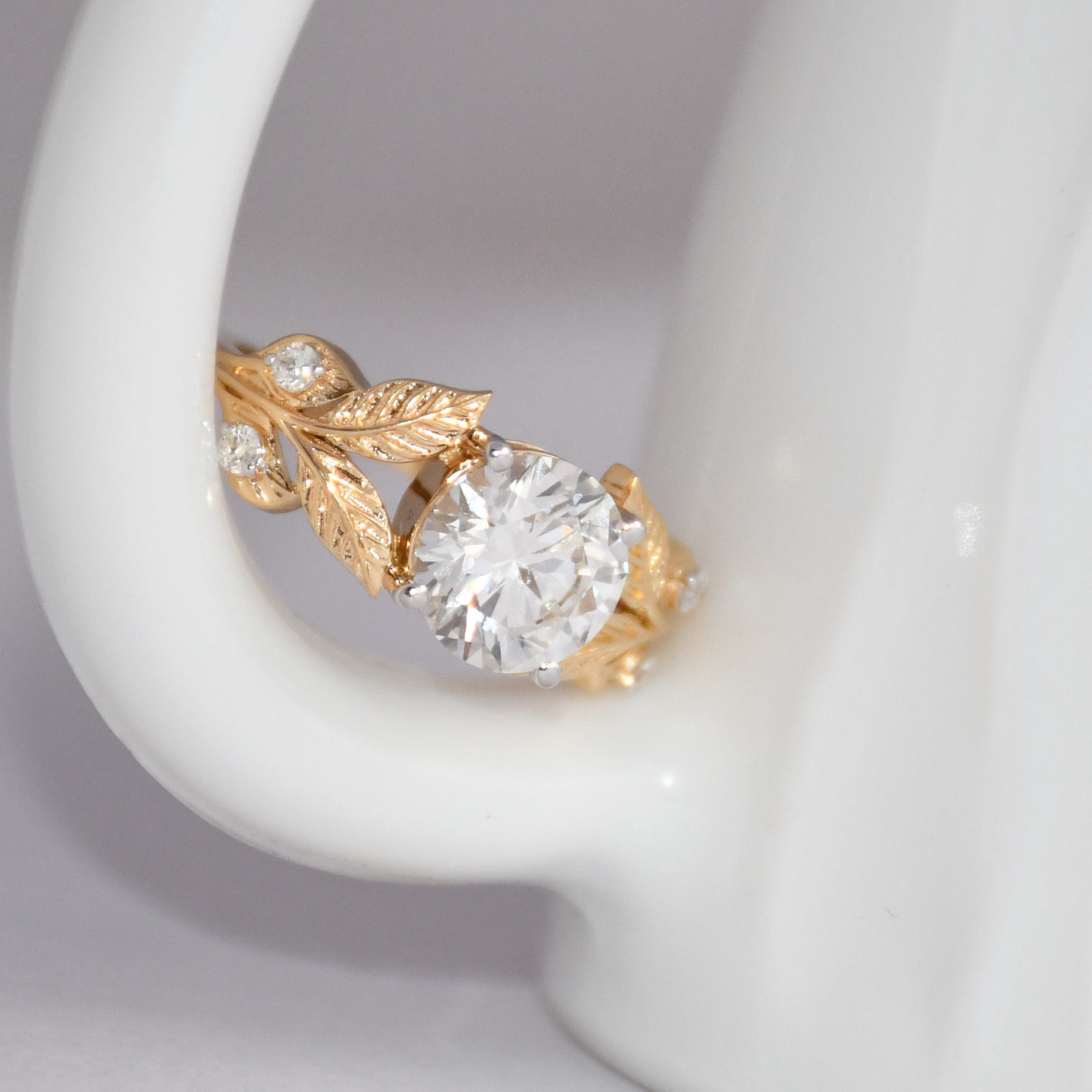 Gold ring with a lab grown diamond on a gray background.