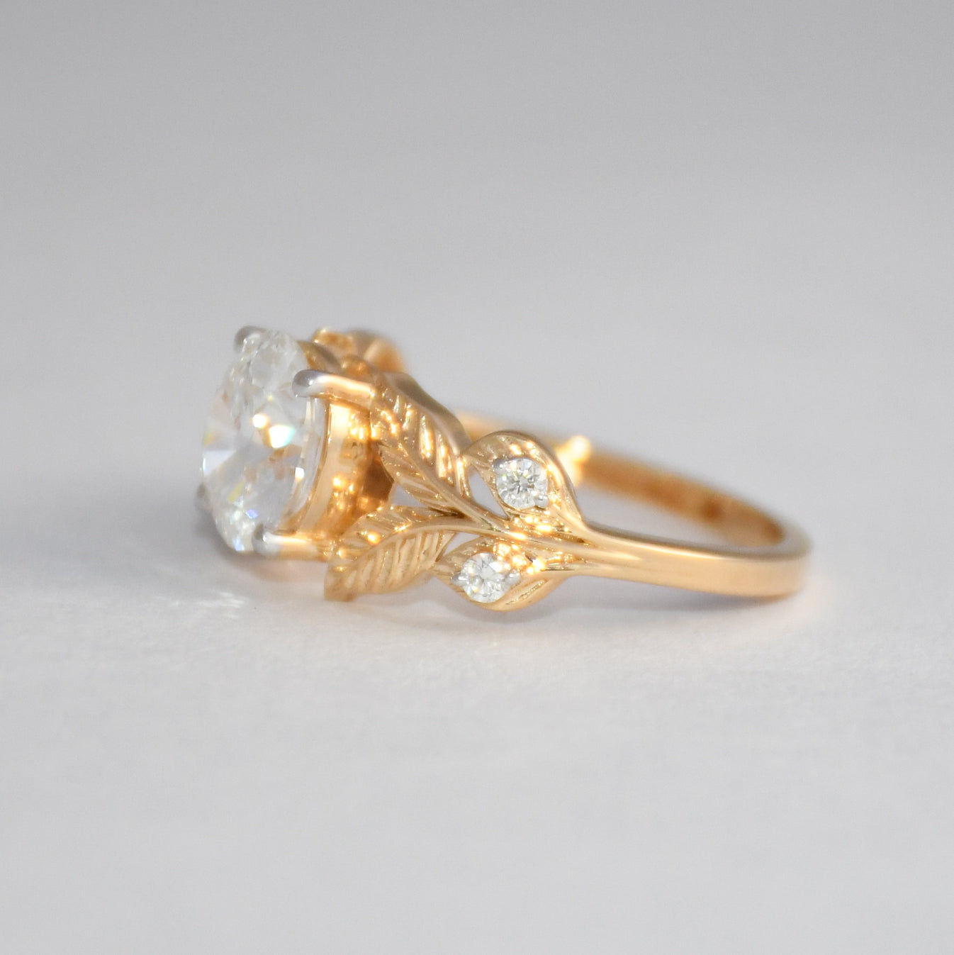 Gold ring with lab grown diamond on a gray background.