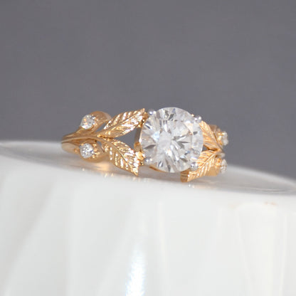 Gold ring with a lab grown diamond on a white surface and gray background.