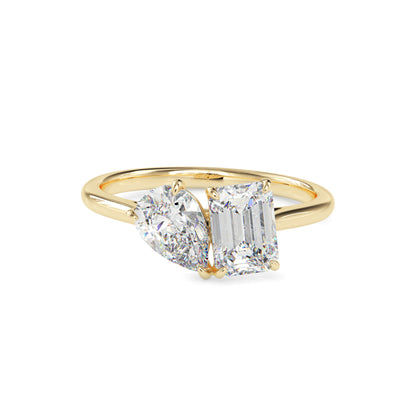 Gold ring with two lab grown diamonds- one pear shape and other baguette shape, on a white background