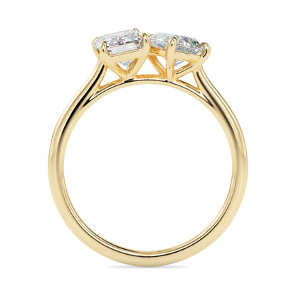 Gold ring with two lab grown diamonds- one pear shape and other baguette shape, on a white background.