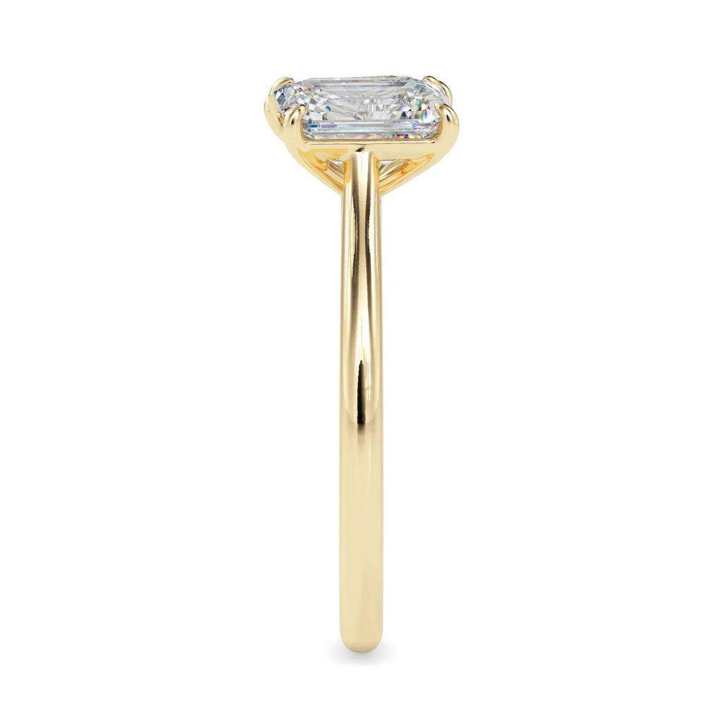 Gold ring with two lab grown diamonds- one pear shape and other baguette shape, on a white background.