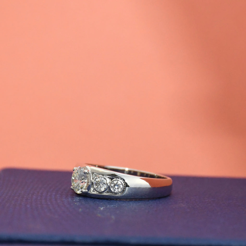 White gold ring with lab diamonds on a textured surface with a pinkish-brown background