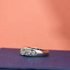 White gold ring with lab diamonds on a textured surface with a pinkish-brown background