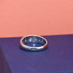 White gold ring on a textured blue surface with a pink background