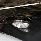 White gold ring with lab diamonds on a black phone case with feathers in the background