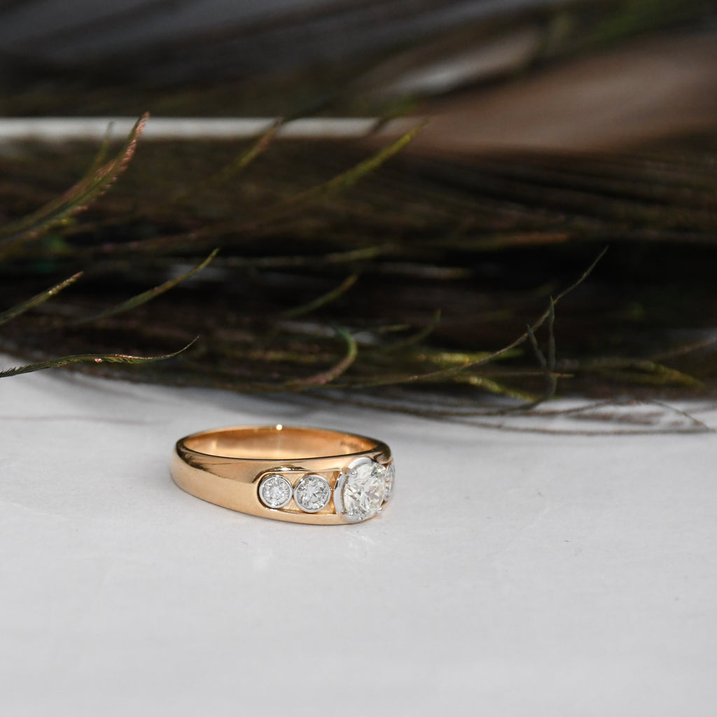 Gold ring with lab diamonds on a white surface with feathers in the background