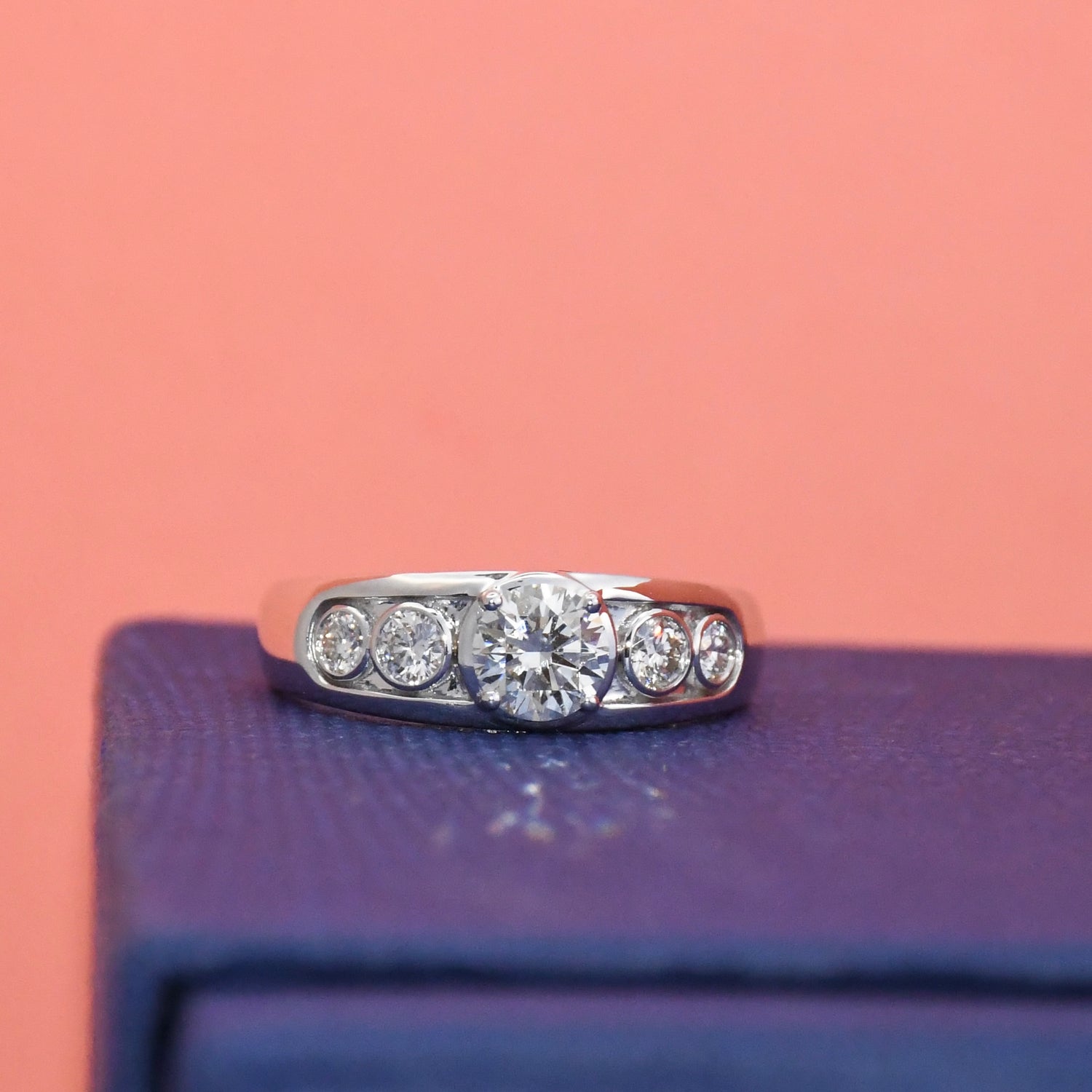 Lab diamond ring on a purple surface with a pink background