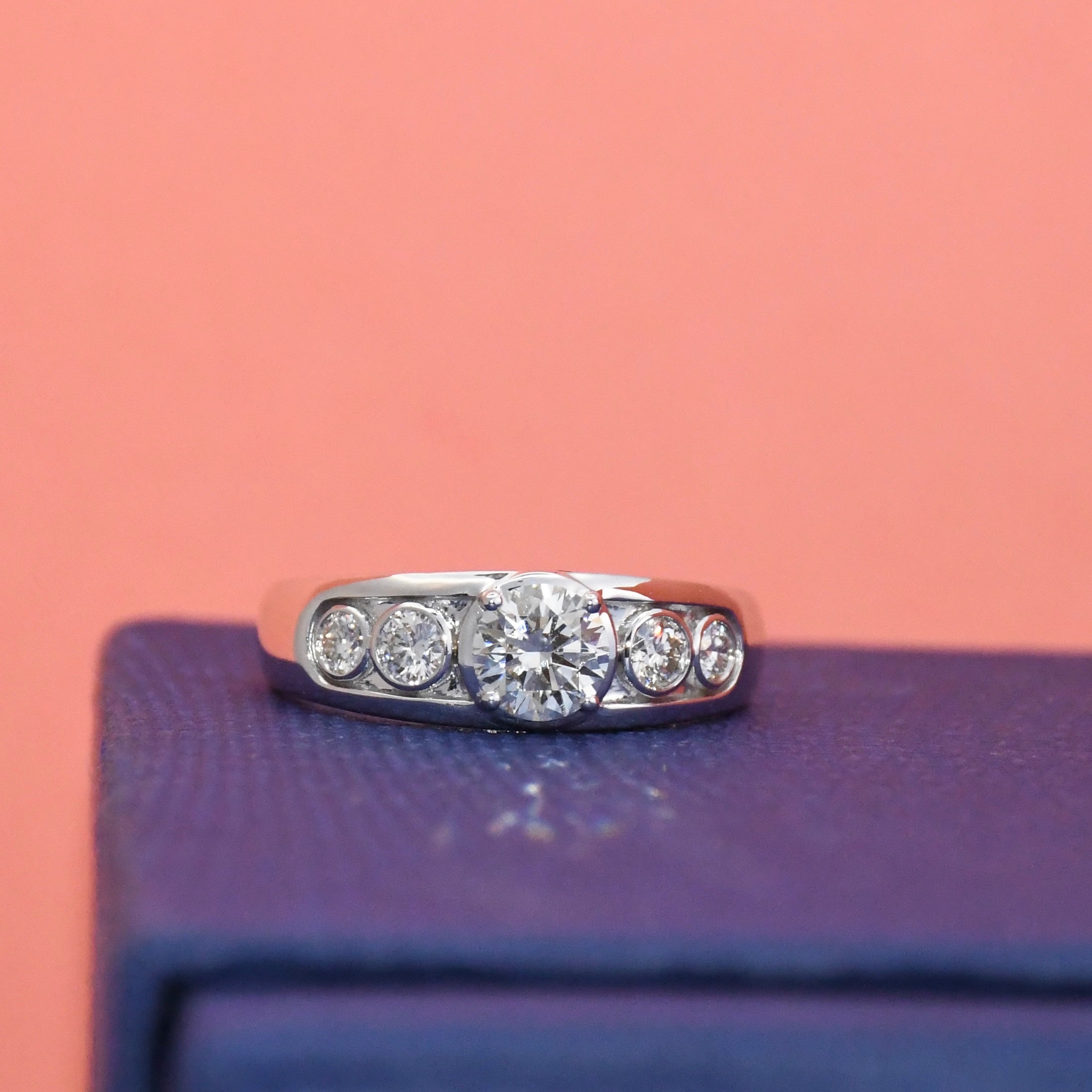 Lab diamond ring on a purple surface with a pink background