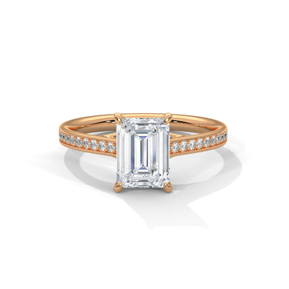Gold ring with a large baguette-cut diamond and smaller diamonds on the band against a white background