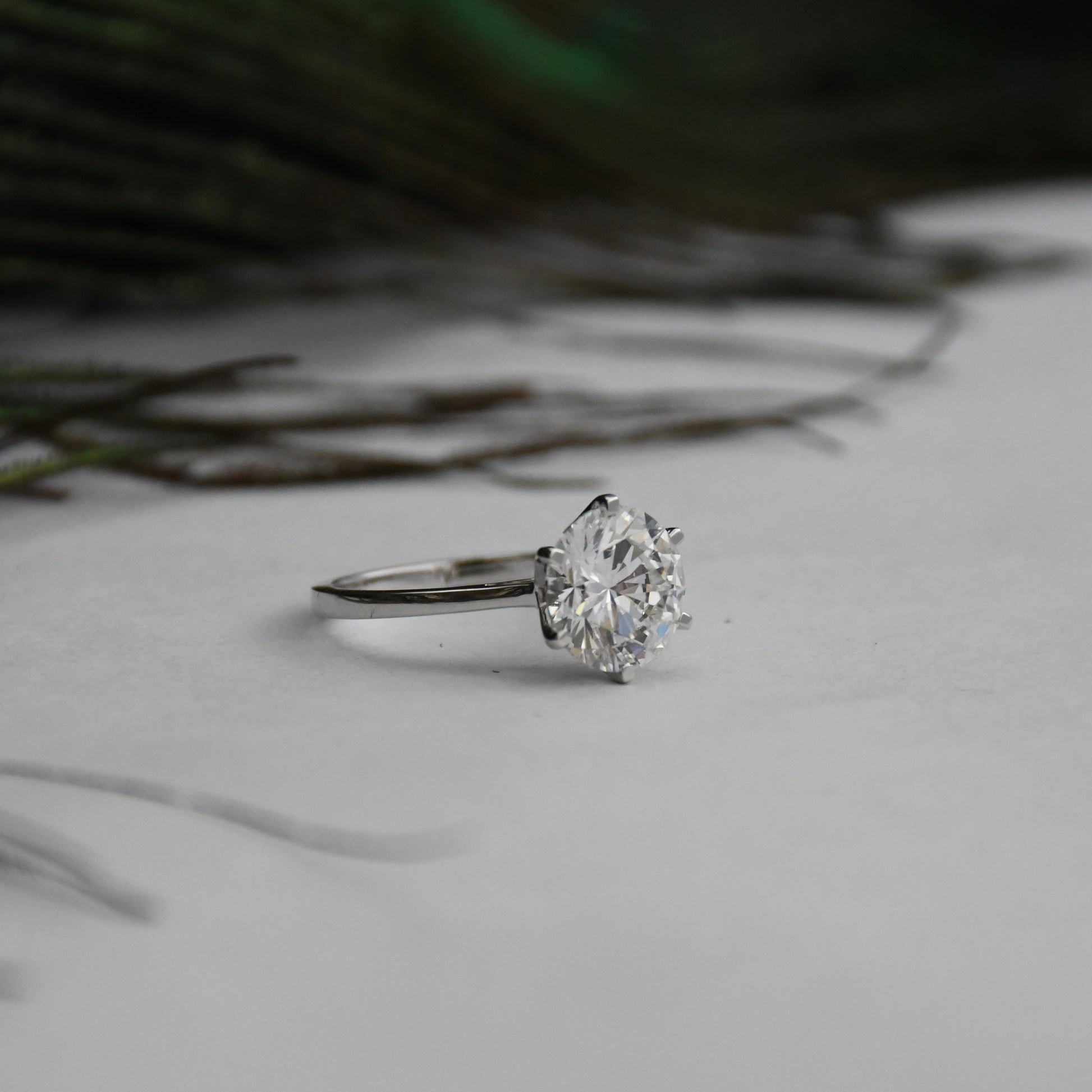 Lab grown solitaire diamond ring on a light surface with blurred natural background