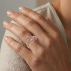 Hand wearing a rose gold ring with a diamond on a neutral background