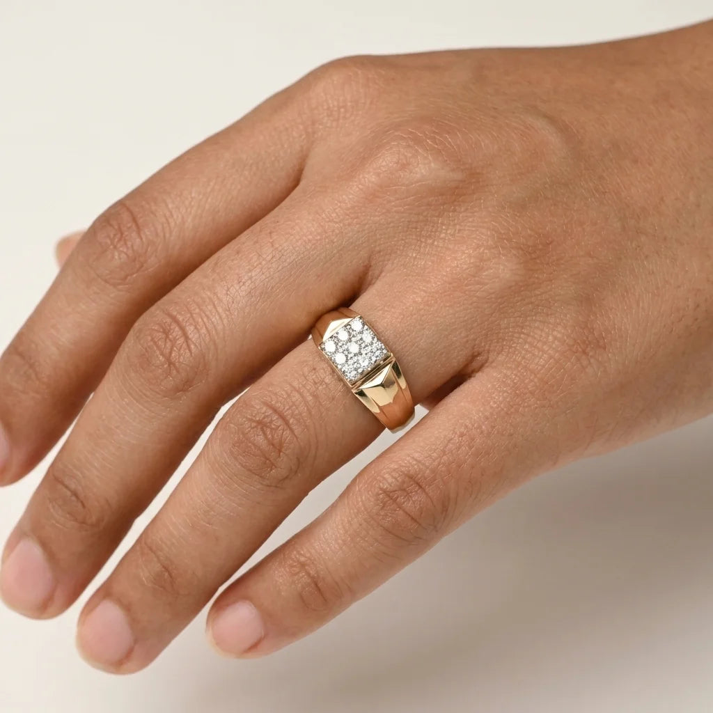 A close-up of a hand wearing a gold ring with a pavé diamond setting on the ring finger, photographed against a plain light background.