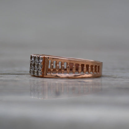 A gold diamond ring is displayed on a grey surface.