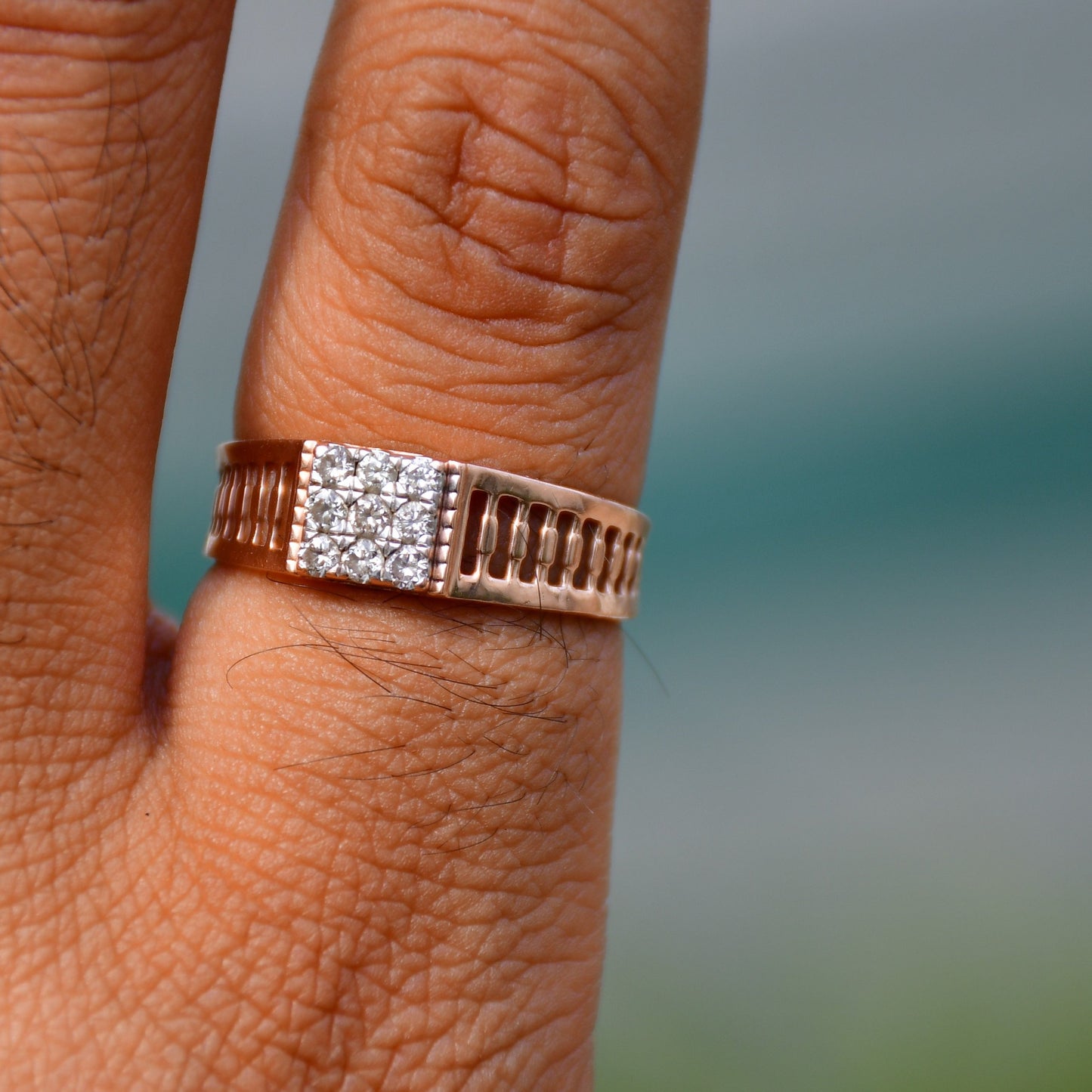 A man's hand displaying a gold diamond ring worn in his finger.