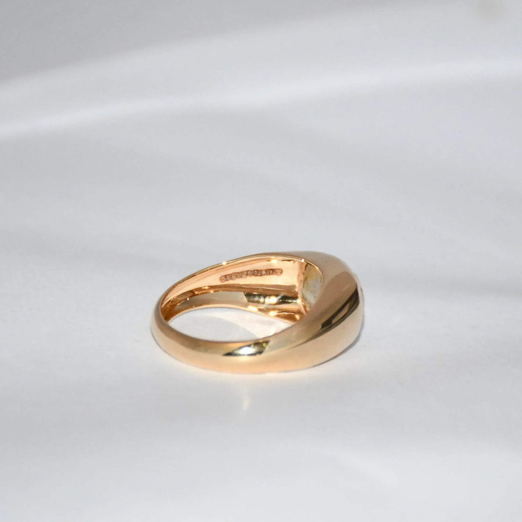 A gold ring with natural sapphire gemstone is displayed on a white surface.