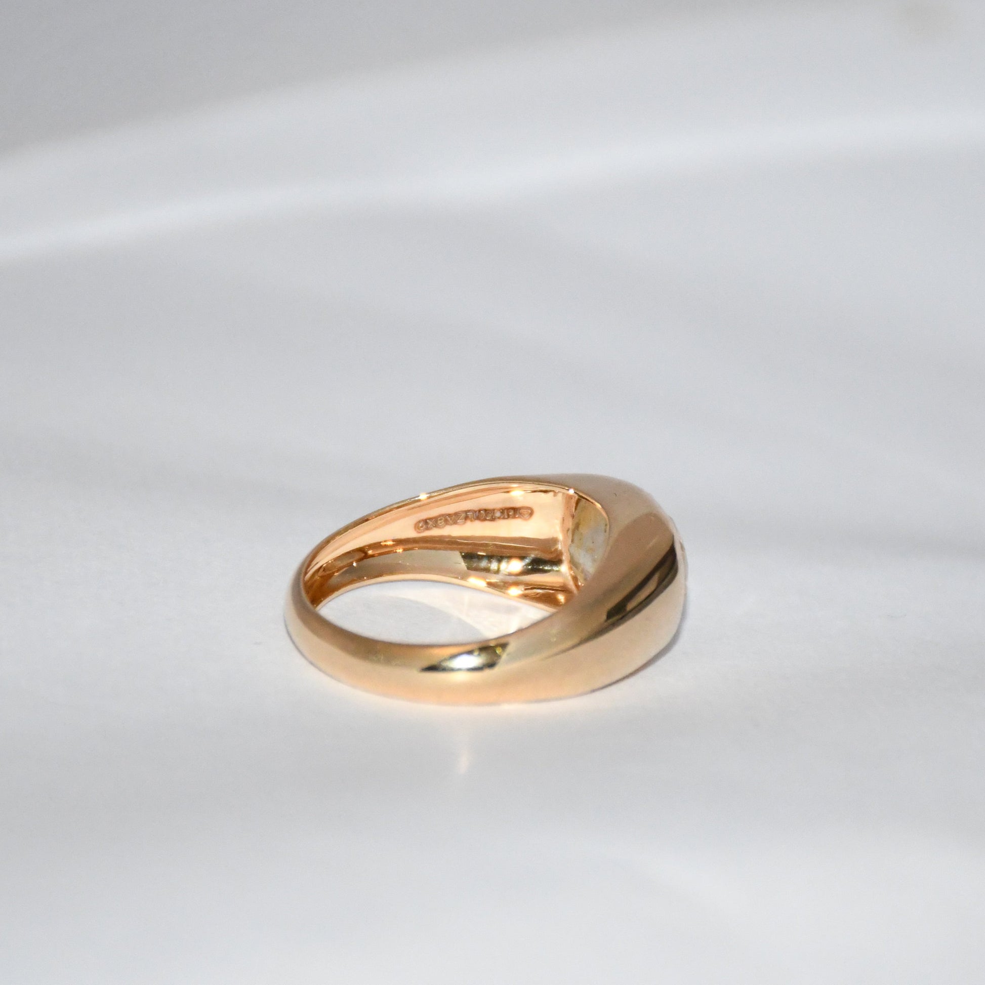 A gold ring with natural sapphire gemstone is displayed on a white surface.