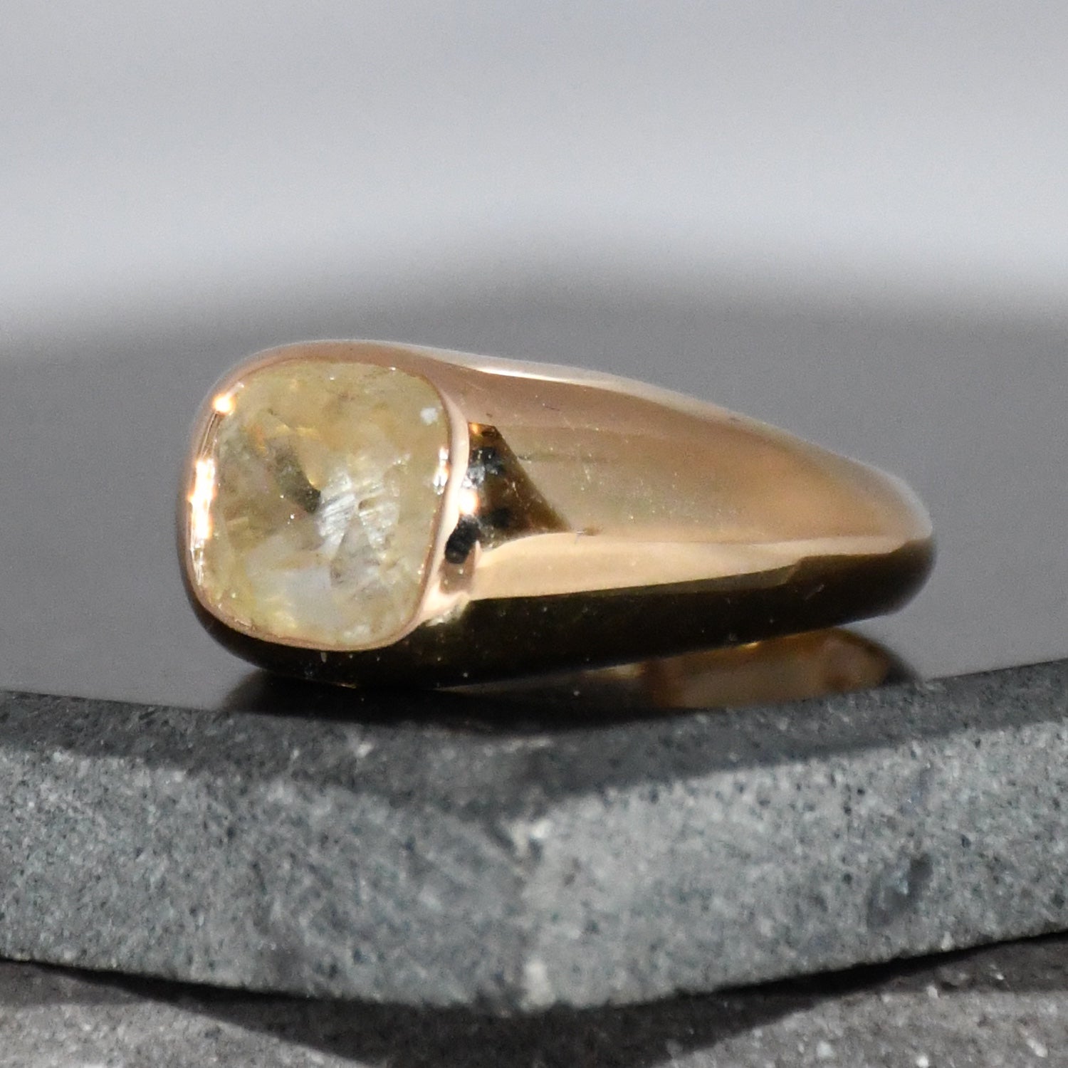 A gold ring with natural sapphire gemstone is displayed on a black surface.
