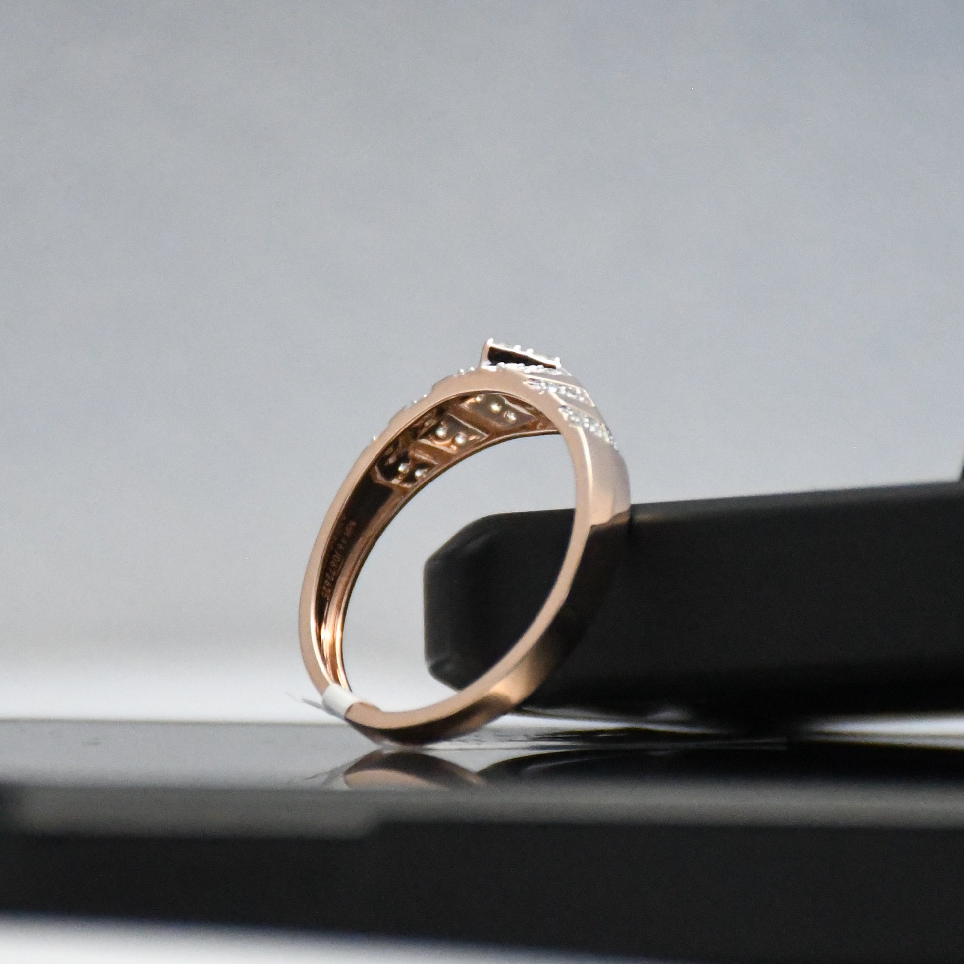 Rose gold ring with engraving on a reflective surface
