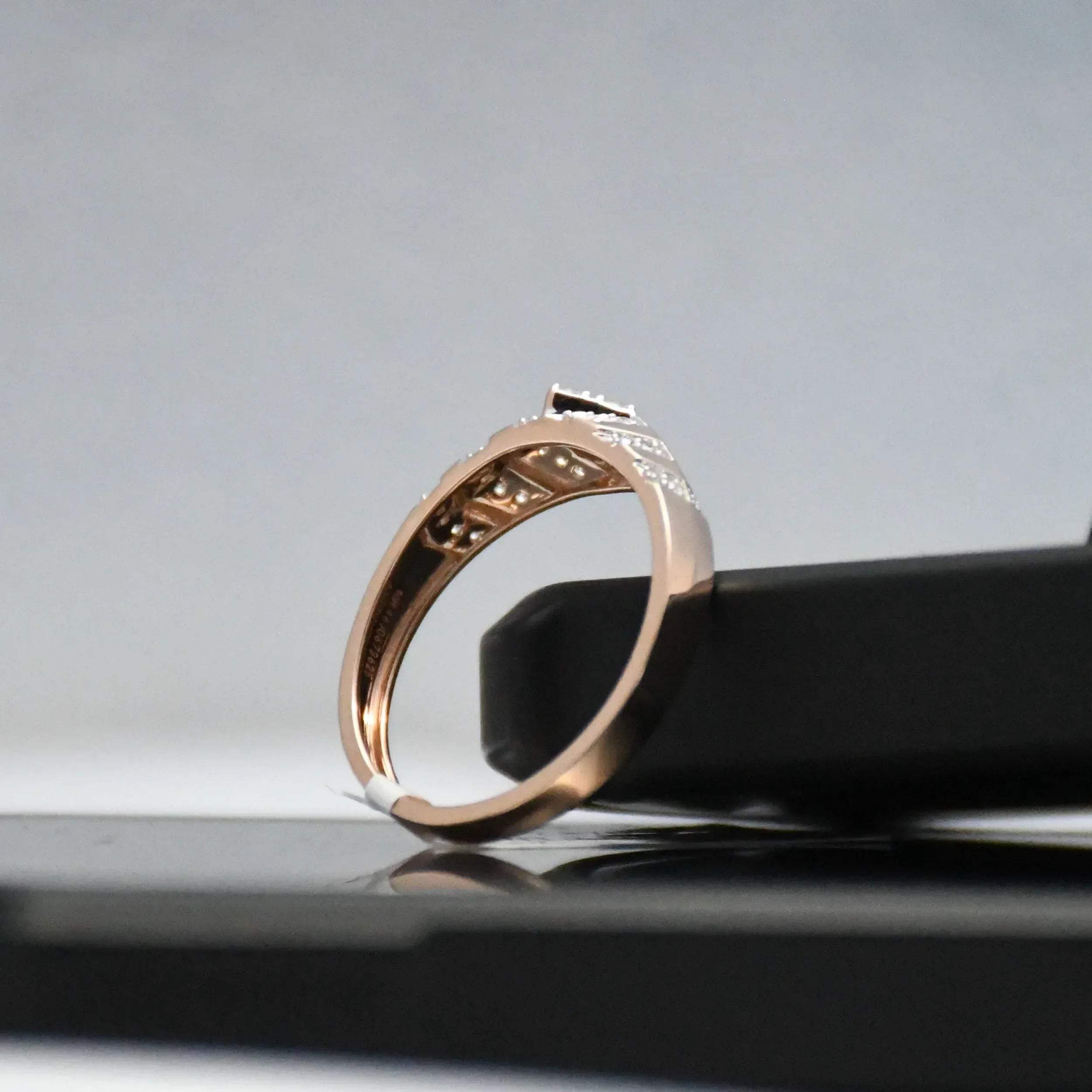 Rose gold ring with engraving on a reflective surface