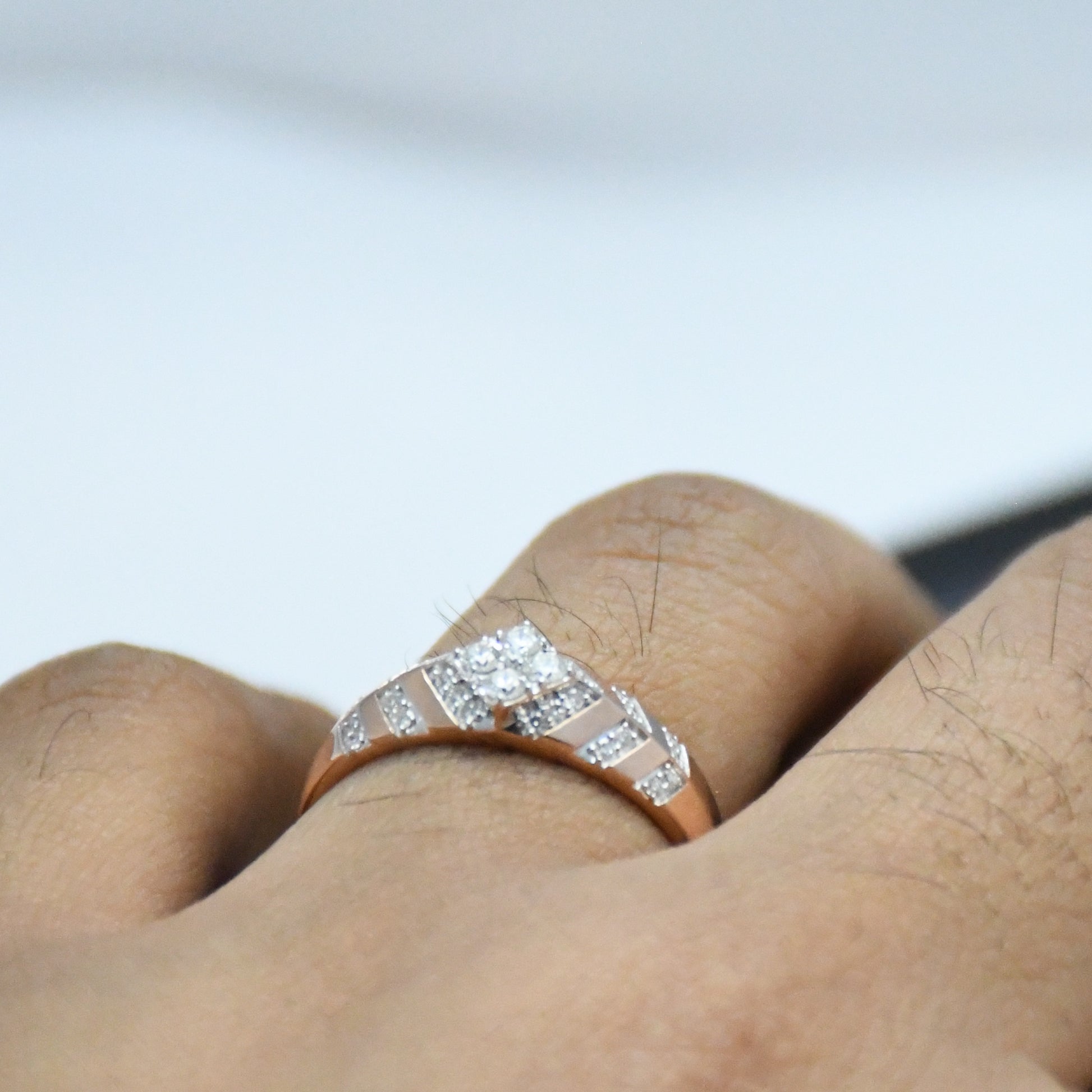 gold ring with diamonds on a finger against a blurred background