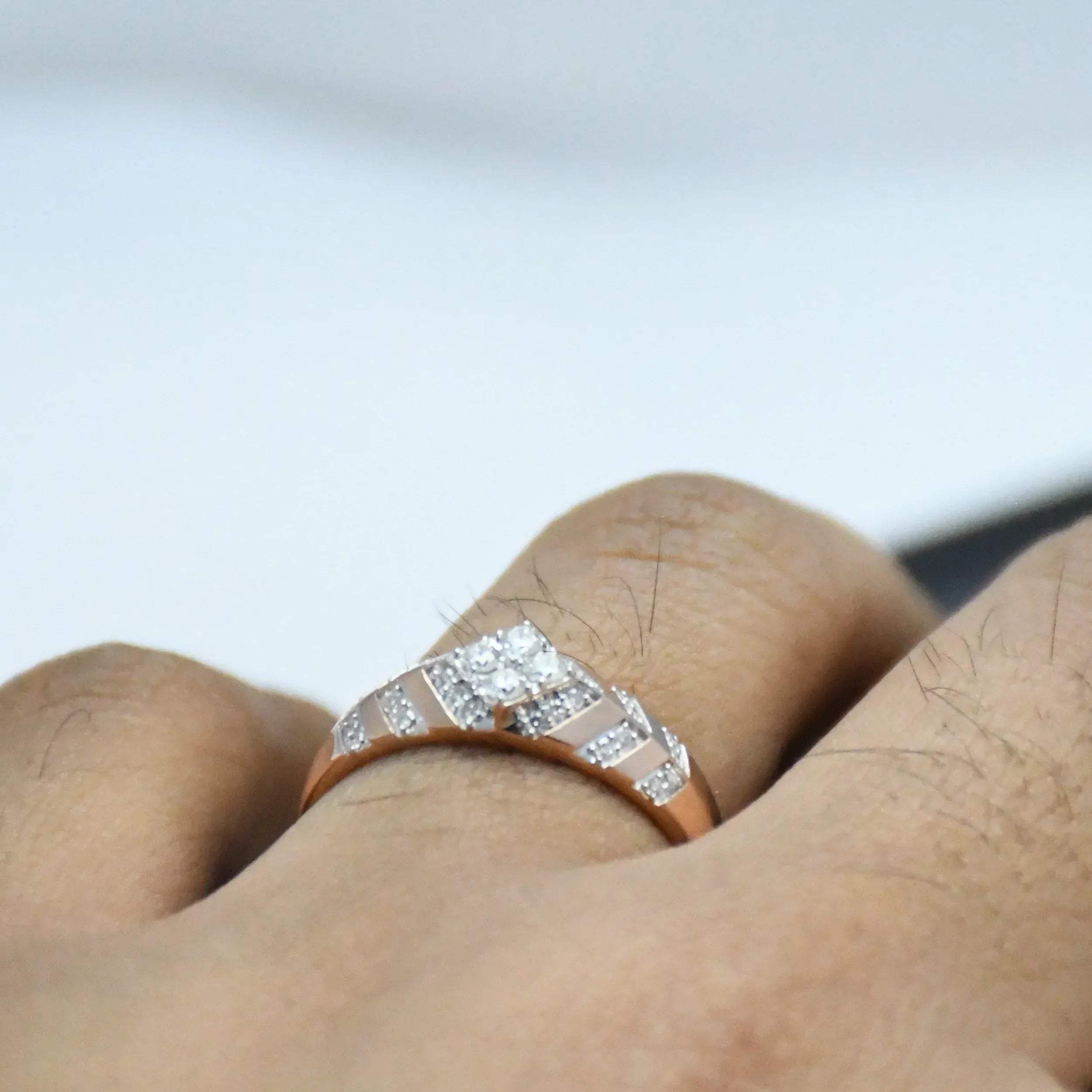 gold ring with diamonds on a finger against a blurred background