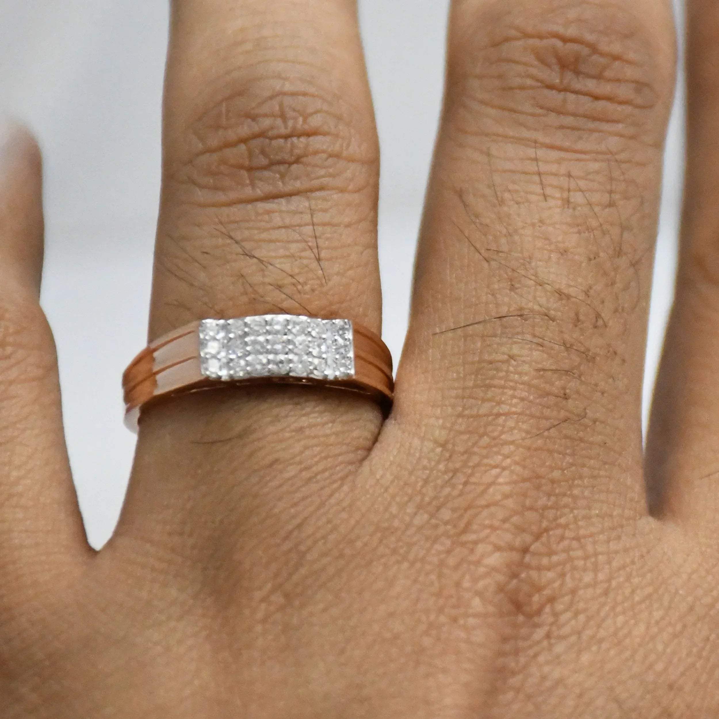 Close-up of a hand wearing a diamod ring with a gold band on a white background