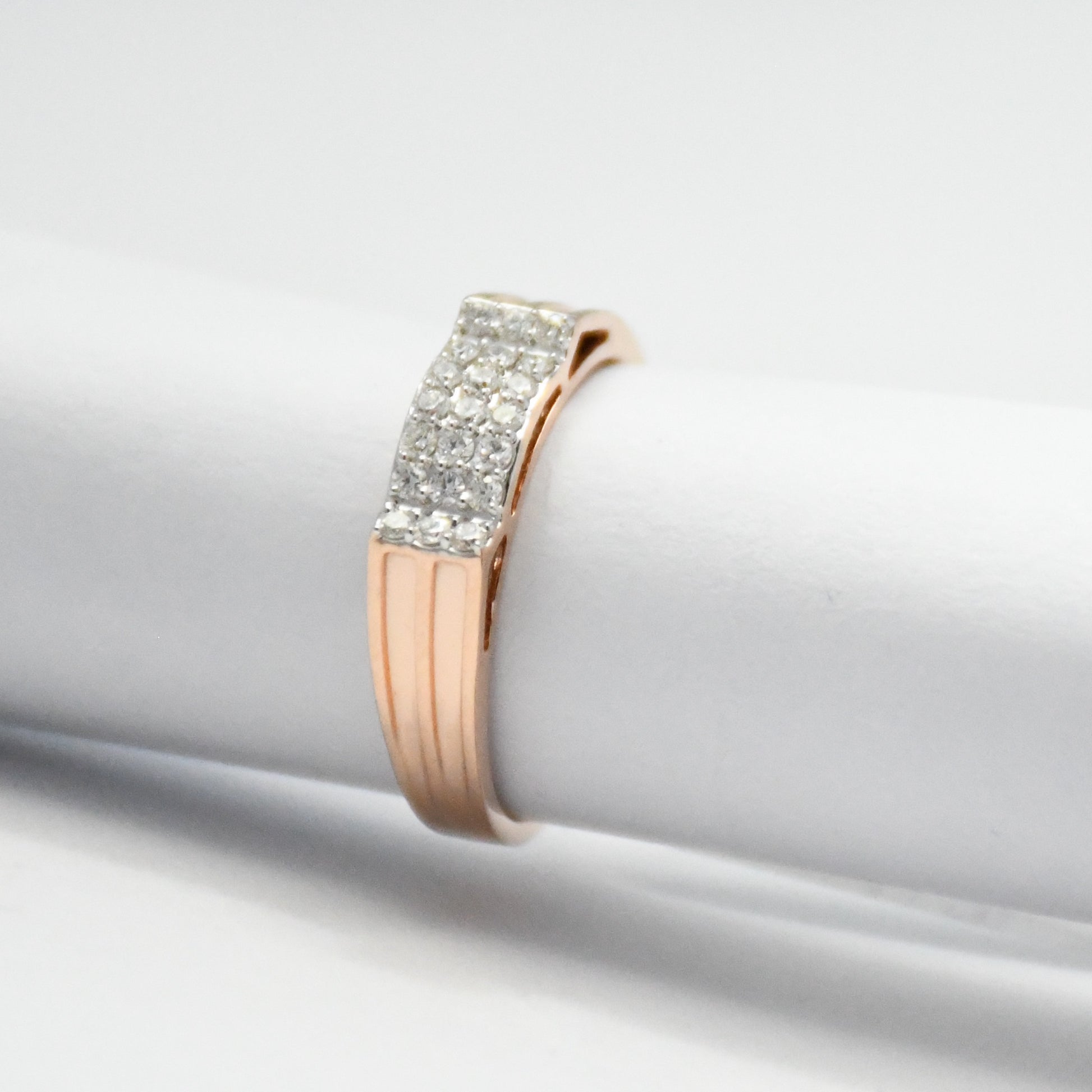 Rose gold ring with diamond accents on a light gray background