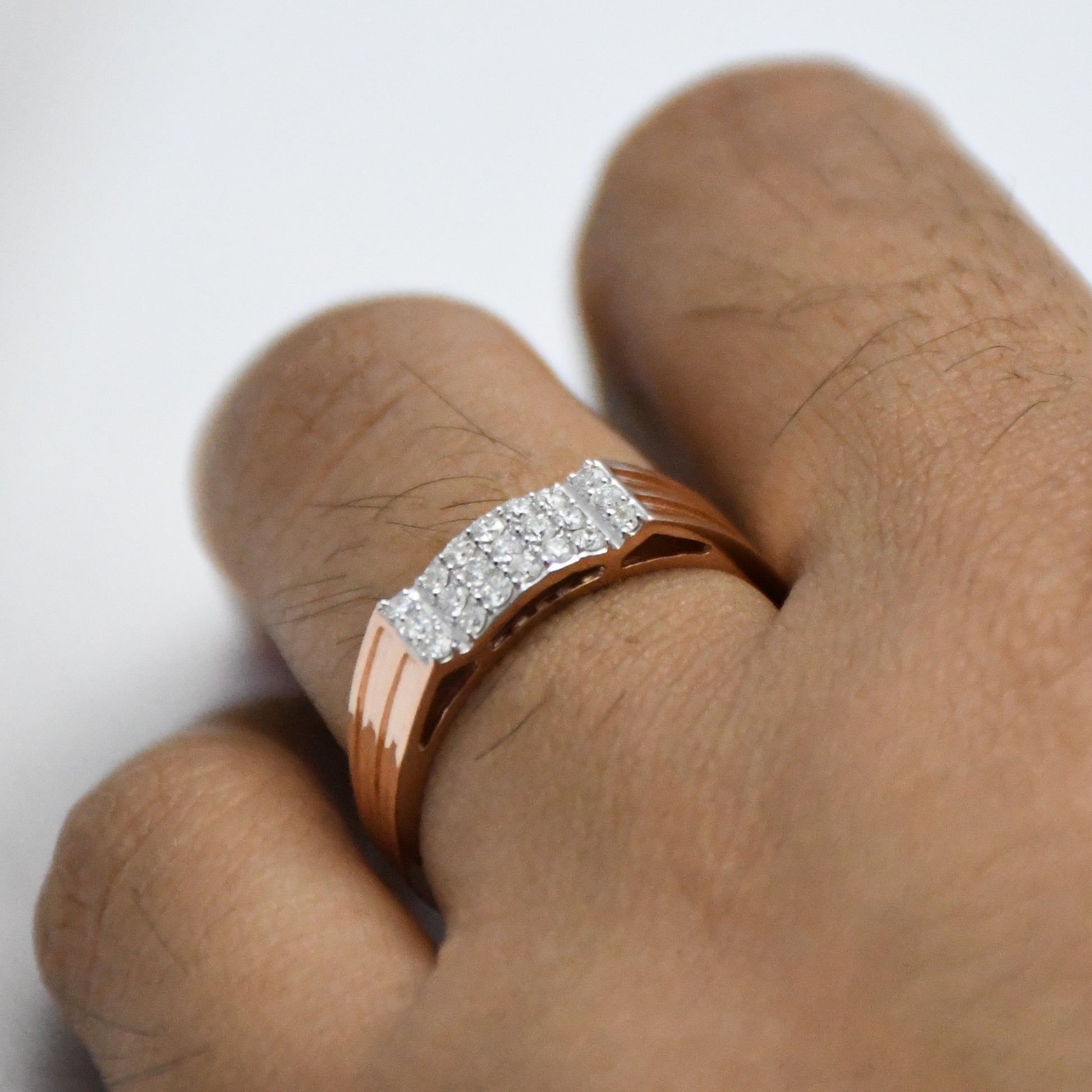 gold ring with diamonds on a finger against a white background