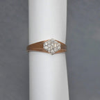 gold ring with diamond on a white cylindrical stand against a gray background