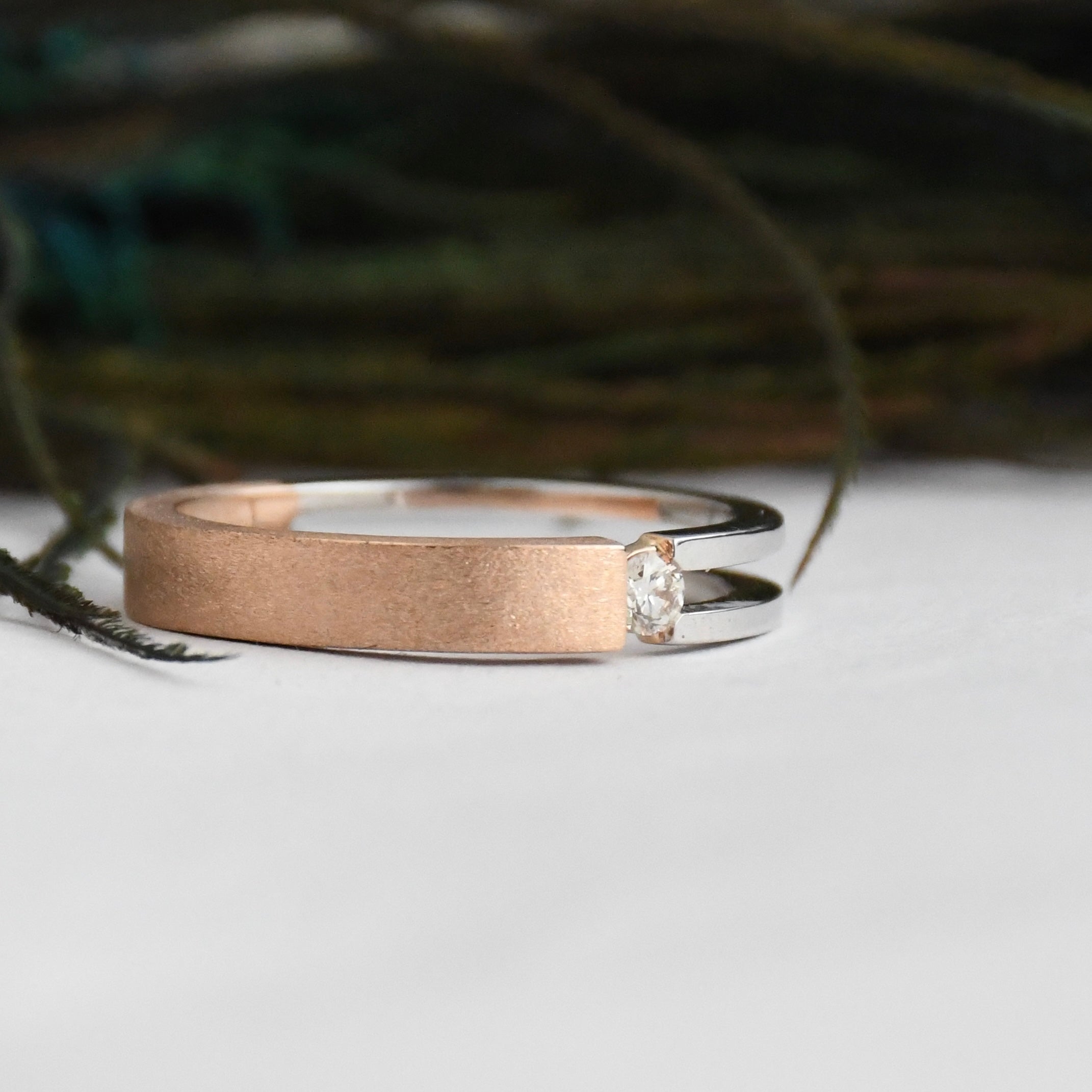 Two tone gold ring with a diamond on a white surface