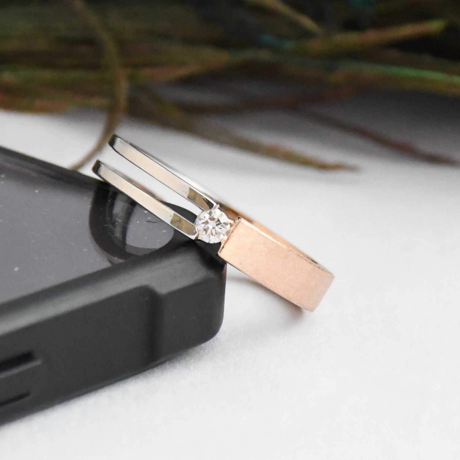 Two tone gold rings with a natural diamond on a white surface