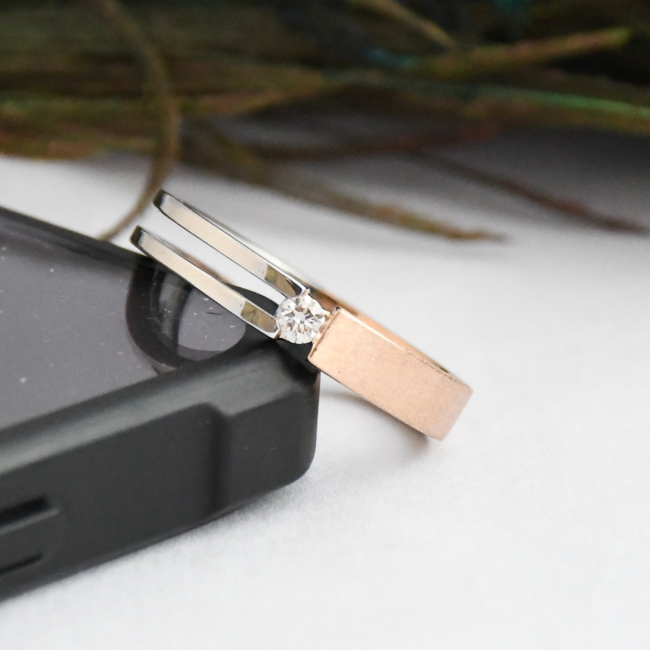 Two tone gold rings with a natural diamond on a white surface