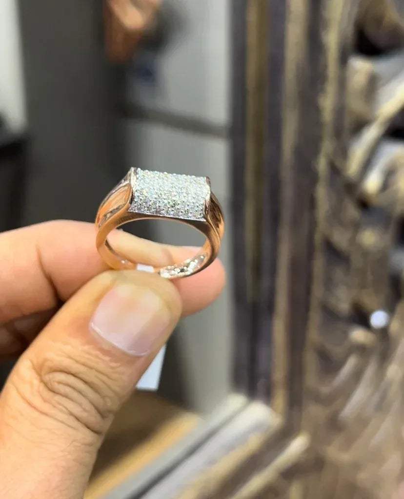 A man's hand holding a diamond men's ring with a gold band, featuring prominent diamonds centerpiece.