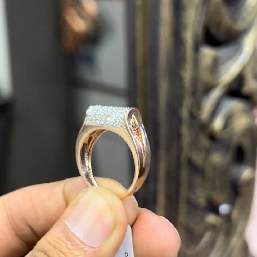 A man's hand holding a diamond men's ring with a gold band, featuring prominent diamonds centerpiece.