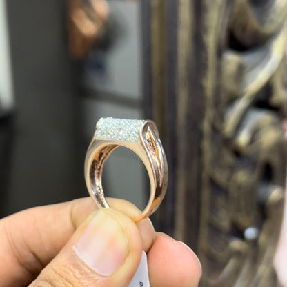 A man's hand holding a diamond men's ring with a gold band, featuring prominent diamonds centerpiece.