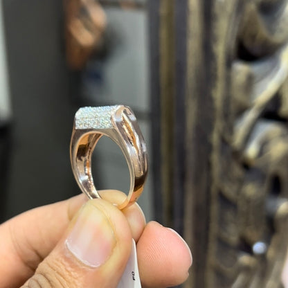 A man's hand holding a diamond men's ring with a gold band, featuring prominent diamonds centerpiece.