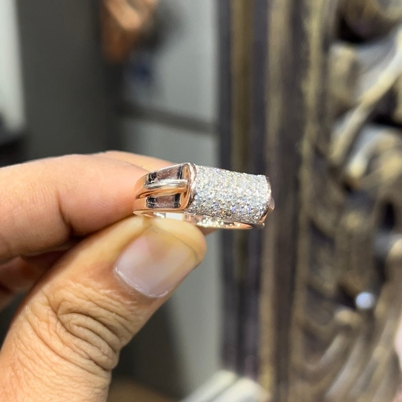 A man's hand holding a diamond men's ring with a gold band, featuring prominent diamonds centerpiece.