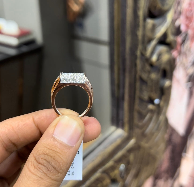 A man's hand holding a diamond men's ring with a gold band, featuring prominent diamonds centerpiece.