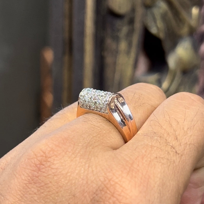 A man's hand holding a diamond men's ring with a gold band, featuring prominent diamonds centerpiece.