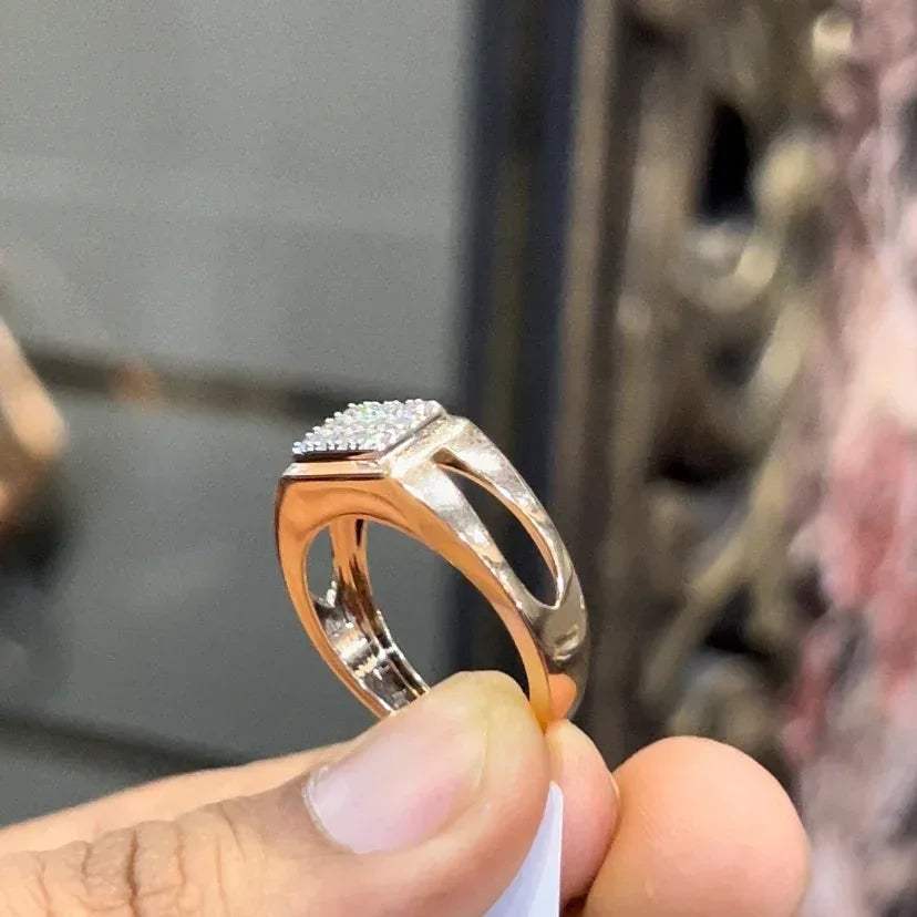 A man's hand displaying a diamond ring with a gold band.