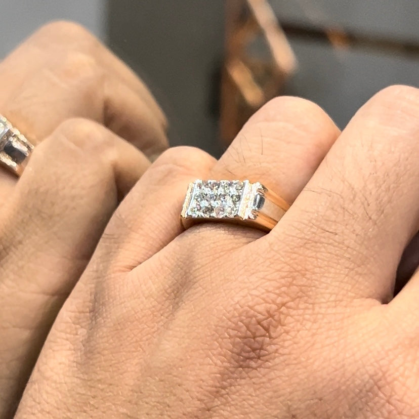 Men’s diamond ring in dual-tone gold with bold rectangular cluster of round diamonds at the center, flanked by sleek metal panels, shown worn on finger.