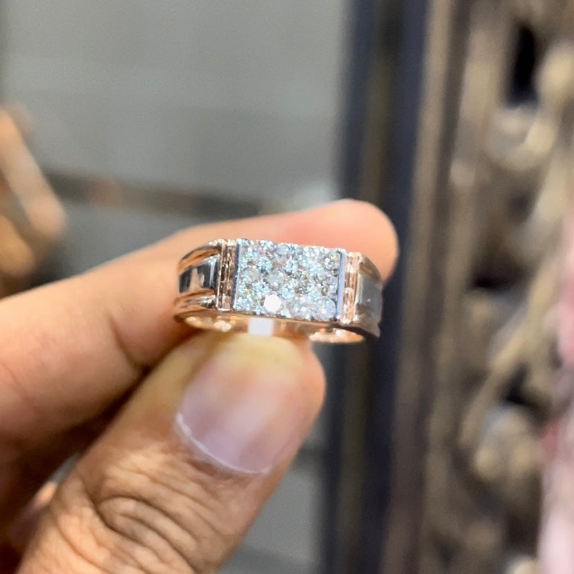 Men’s diamond ring in dual-tone gold with bold rectangular cluster of round diamonds at the center, flanked by sleek metal panels, shown by a person's hand.