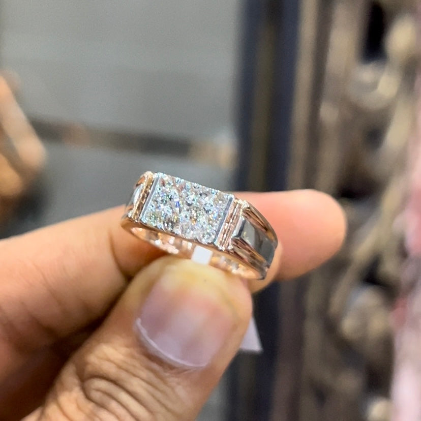 Men’s diamond ring in dual-tone gold with bold rectangular cluster of round diamonds at the center, flanked by sleek metal panels, shown by a person's hand.